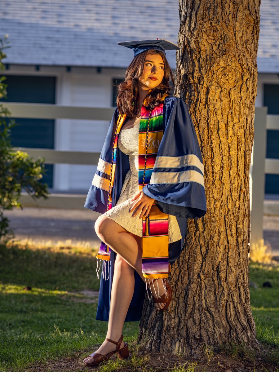 Graduate posing beside a tree in warm evening light